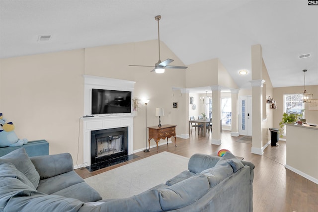 living room with decorative columns, vaulted ceiling, a wealth of natural light, and light hardwood / wood-style floors