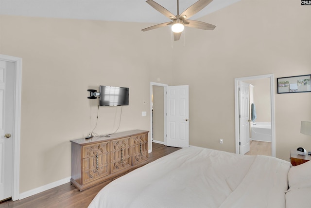 bedroom with connected bathroom, hardwood / wood-style flooring, ceiling fan, and a towering ceiling