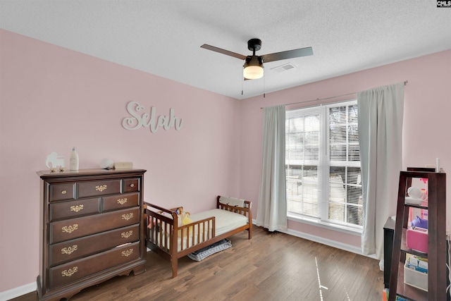 bedroom with ceiling fan, wood-type flooring, multiple windows, and a textured ceiling