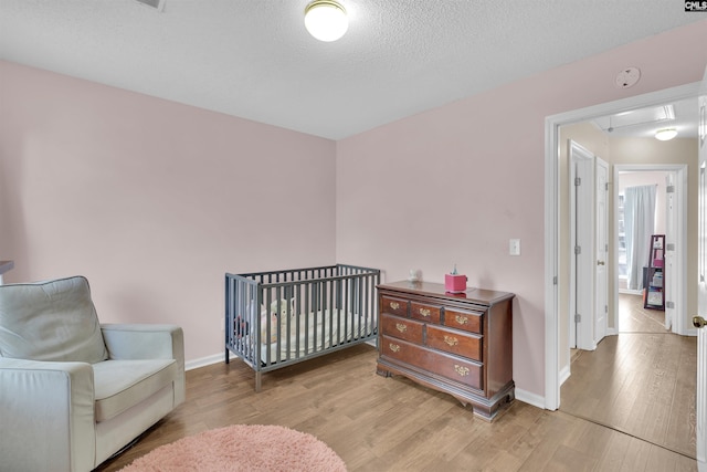 bedroom with light hardwood / wood-style floors and a textured ceiling