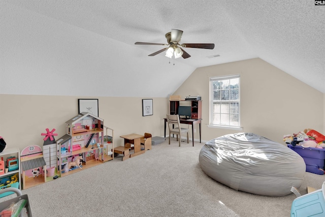 recreation room featuring vaulted ceiling, carpet flooring, ceiling fan, and a textured ceiling