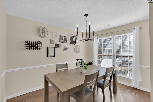 dining room featuring hardwood / wood-style flooring, a chandelier, and a textured ceiling