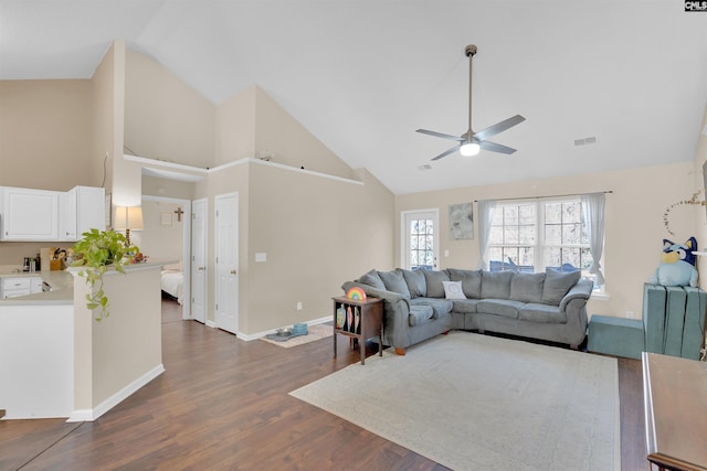 living room with dark wood-type flooring, ceiling fan, and high vaulted ceiling