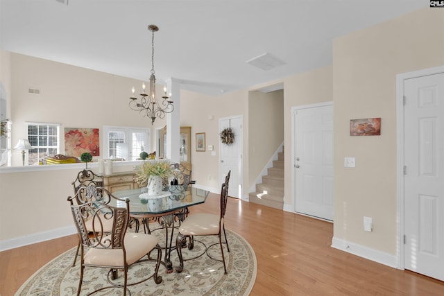 dining space with an inviting chandelier and light hardwood / wood-style flooring