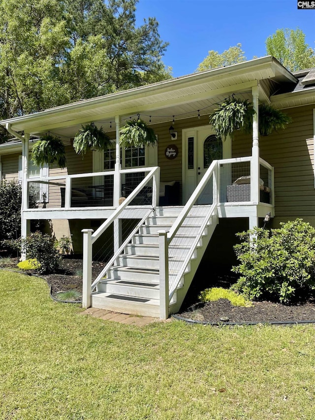 entrance to property featuring a yard and covered porch