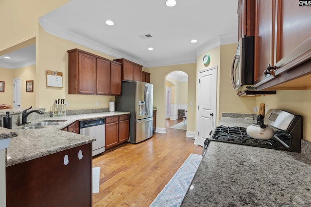 kitchen featuring appliances with stainless steel finishes, sink, ornamental molding, light stone counters, and light hardwood / wood-style floors