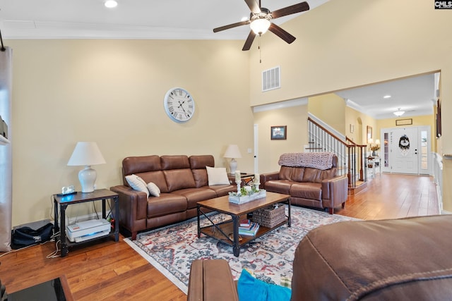 living room with crown molding, a towering ceiling, and hardwood / wood-style floors