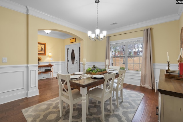 dining room with ornamental molding, dark hardwood / wood-style floors, and an inviting chandelier