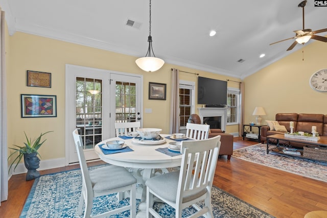 dining area with crown molding, dark wood-type flooring, ceiling fan, and vaulted ceiling