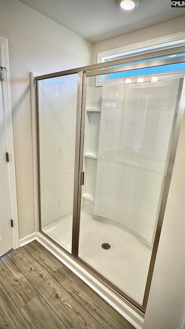 bathroom featuring wood-type flooring and a shower with shower door