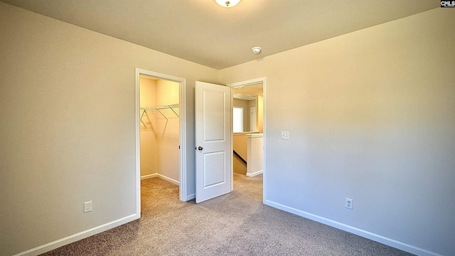 unfurnished bedroom featuring a spacious closet, light colored carpet, and a closet