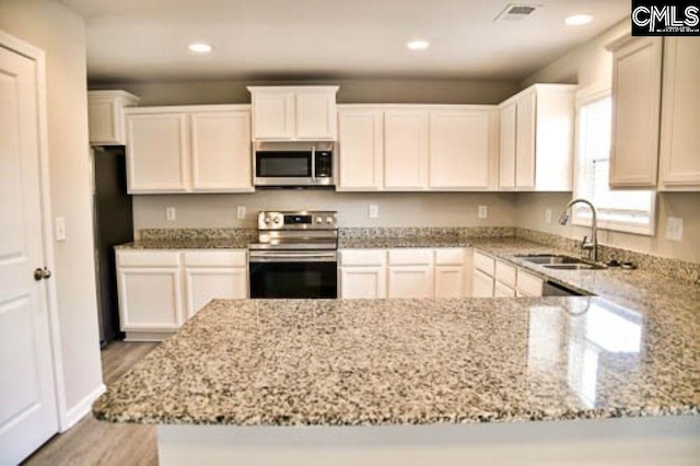 kitchen with sink, light stone counters, white cabinetry, light hardwood / wood-style flooring, and stainless steel appliances