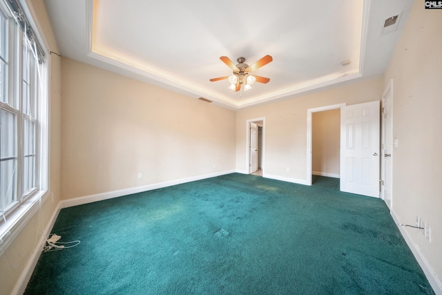 unfurnished room featuring dark colored carpet, ceiling fan, and a tray ceiling