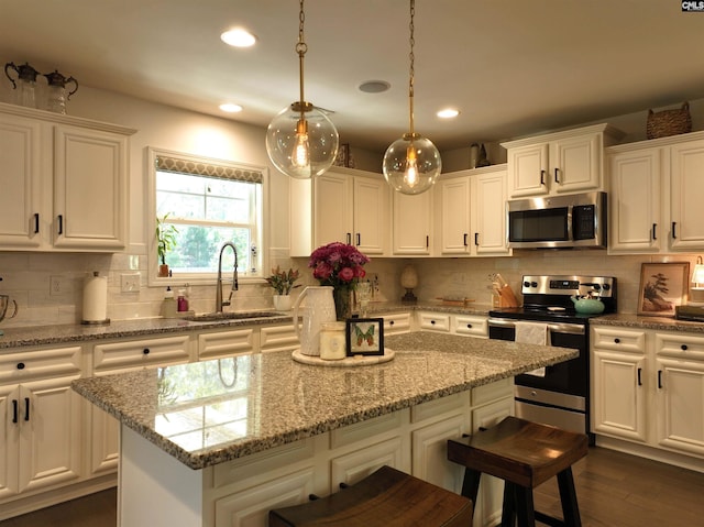 kitchen featuring sink, stainless steel appliances, white cabinets, and a kitchen island