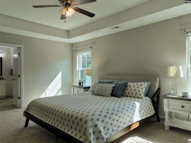 carpeted bedroom featuring ceiling fan and ensuite bath