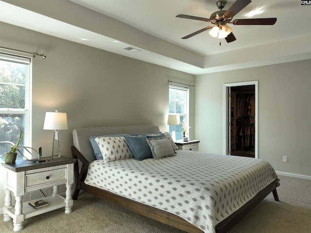 bedroom featuring a spacious closet, ceiling fan, and carpet