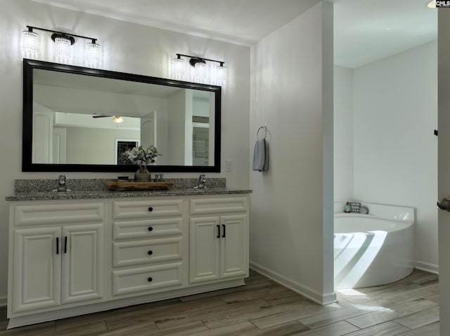 bathroom with a washtub, hardwood / wood-style floors, vanity, and ceiling fan