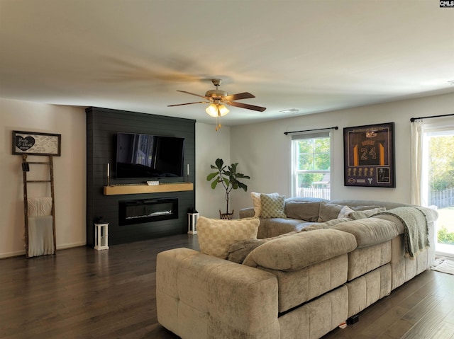 living room featuring dark wood-type flooring, ceiling fan, plenty of natural light, and a fireplace