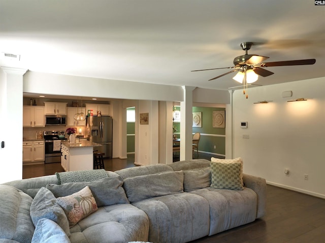 living room featuring dark wood-type flooring and ceiling fan