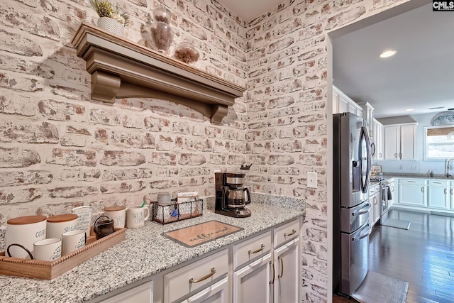 kitchen with white cabinetry, stainless steel appliances, and light stone countertops