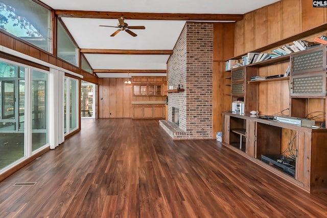 unfurnished living room with vaulted ceiling with beams, a brick fireplace, wooden walls, dark hardwood / wood-style floors, and ceiling fan