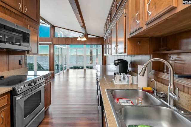 kitchen featuring sink, dark wood-type flooring, appliances with stainless steel finishes, a water view, and lofted ceiling with beams