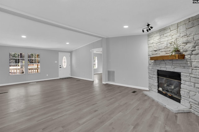 unfurnished living room featuring ornamental molding, a fireplace, light wood-type flooring, and a wealth of natural light