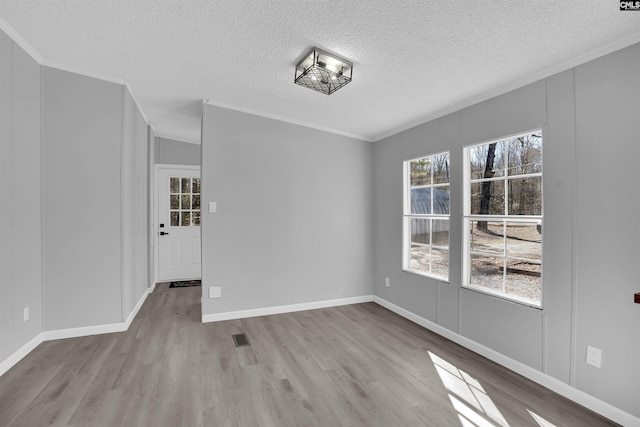 unfurnished dining area with crown molding, light hardwood / wood-style floors, and a textured ceiling