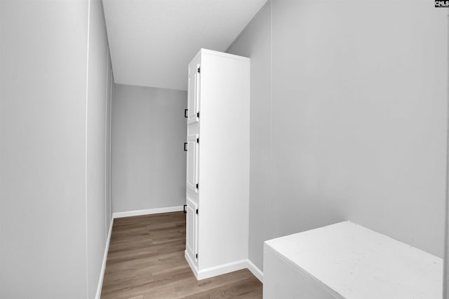 hall with light hardwood / wood-style floors and a textured ceiling