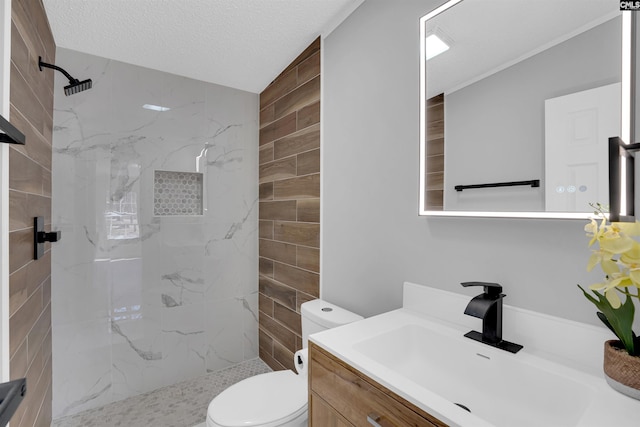 bathroom with vanity, a tile shower, a textured ceiling, and toilet