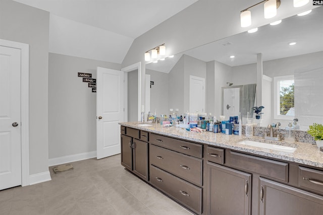 bathroom featuring vaulted ceiling, vanity, tile patterned floors, and walk in shower