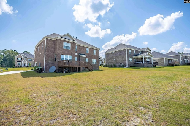 rear view of property with a wooden deck and a lawn