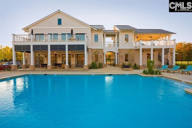 back of property featuring a community pool, a patio area, and a balcony