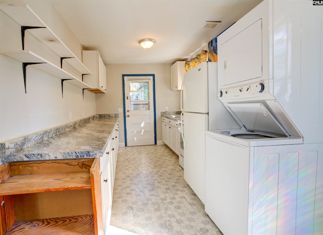 interior space featuring stacked washer / drying machine and white cabinets