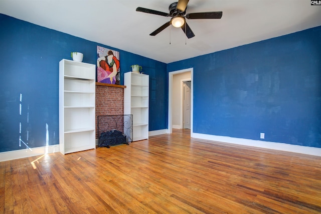 unfurnished living room featuring ceiling fan, hardwood / wood-style floors, and a brick fireplace