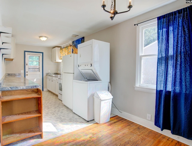 interior space featuring stacked washer / dryer, a wealth of natural light, white cabinets, and light wood-type flooring