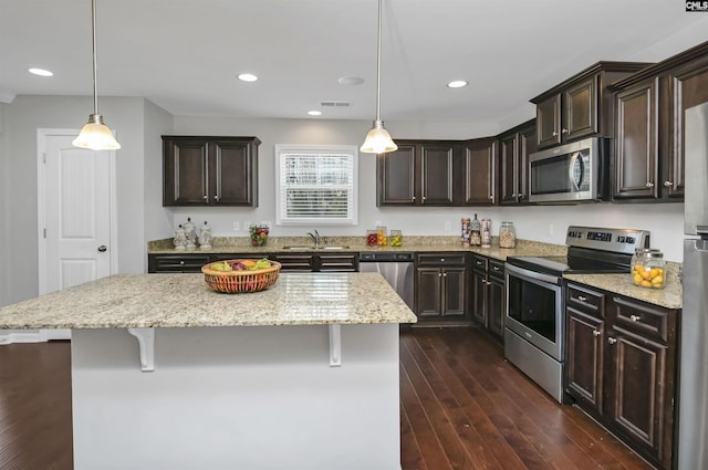 kitchen with stainless steel appliances, a kitchen island, and hanging light fixtures