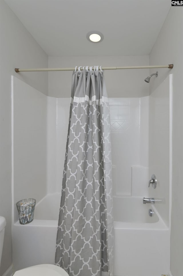 bathroom with shower / bath combination with curtain and toilet