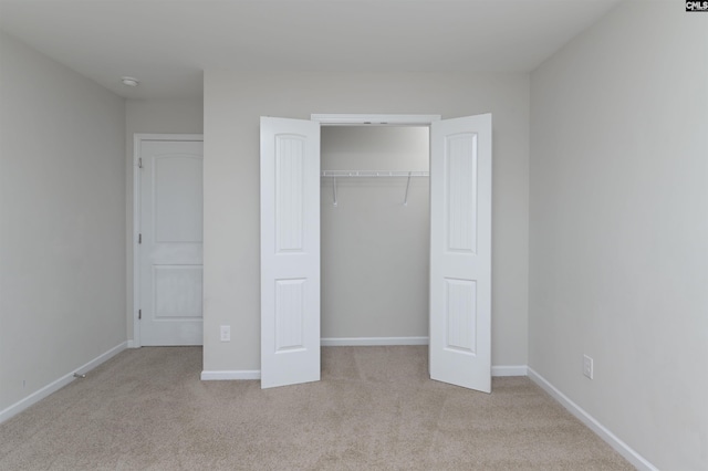 unfurnished bedroom featuring light colored carpet and a closet