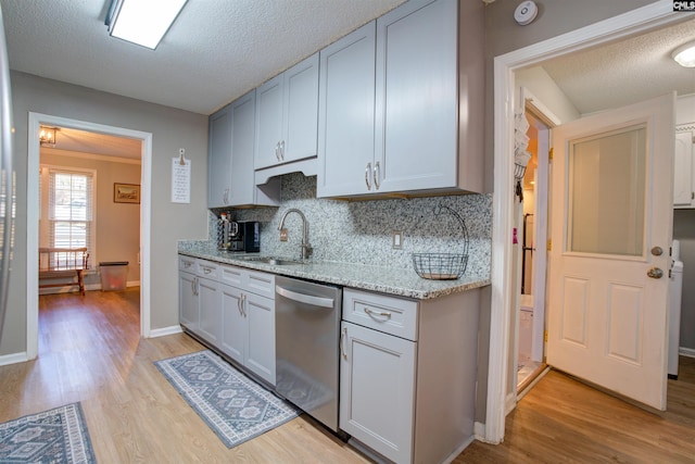 kitchen with sink, dishwasher, backsplash, light stone counters, and light hardwood / wood-style floors