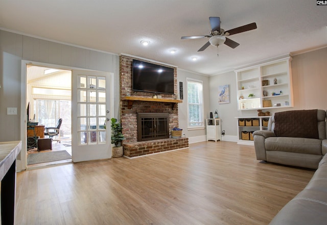 living room with light hardwood / wood-style flooring, a fireplace, ornamental molding, and ceiling fan