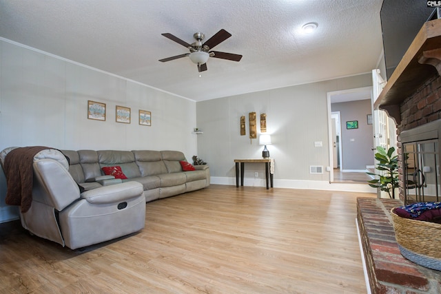 living room featuring ceiling fan, crown molding, light hardwood / wood-style flooring, and a textured ceiling