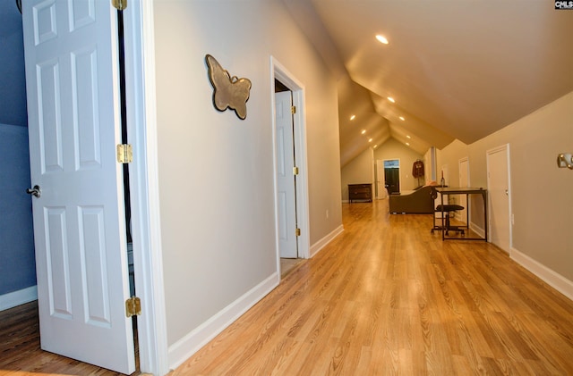 corridor with lofted ceiling and light wood-type flooring