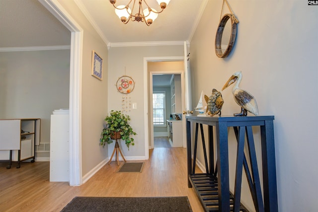 hallway with ornamental molding, wood-type flooring, and a notable chandelier