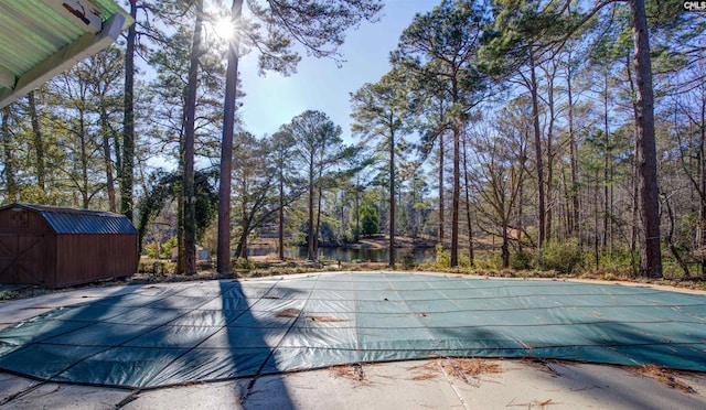 view of swimming pool featuring a water view and a storage unit