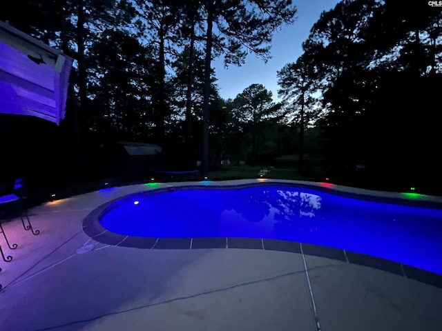 pool at dusk with a patio area