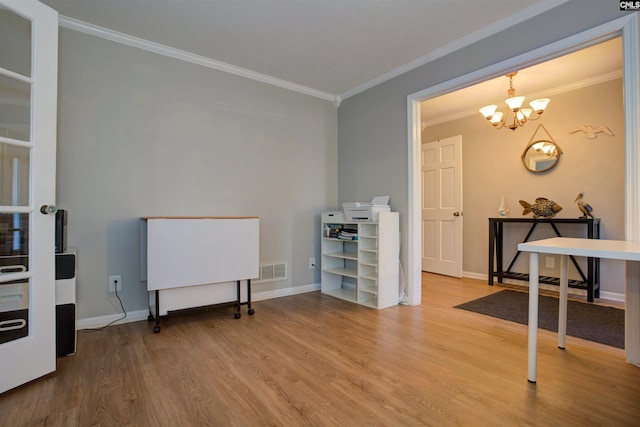 miscellaneous room with wood-type flooring, ornamental molding, and an inviting chandelier