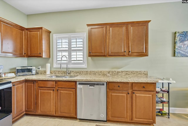 kitchen featuring light stone countertops, appliances with stainless steel finishes, sink, and light tile patterned floors