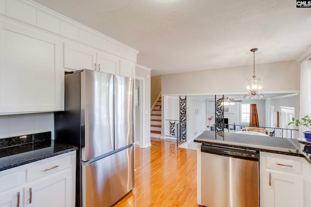 kitchen featuring stainless steel appliances, white cabinetry, and dark stone countertops