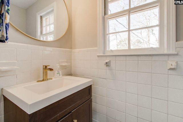 bathroom with a healthy amount of sunlight, vanity, and tile walls